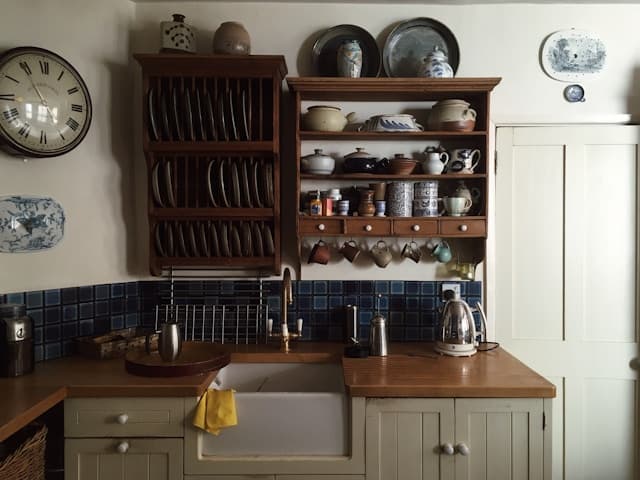 Warm kitchen with vintage ceramics, wooden dish rack, and farmhouse character