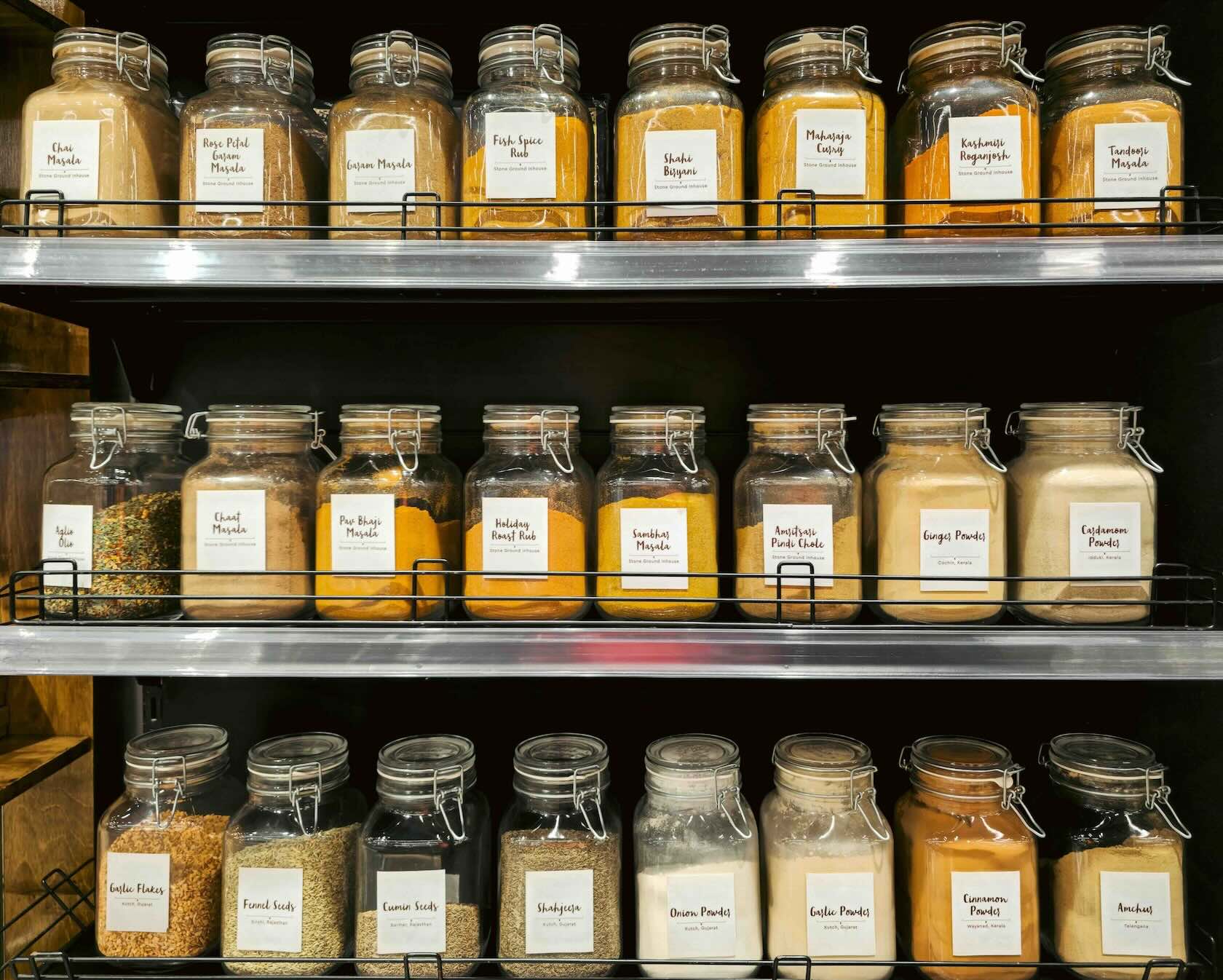 Rows of labeled glass spice jars with amber and golden tones